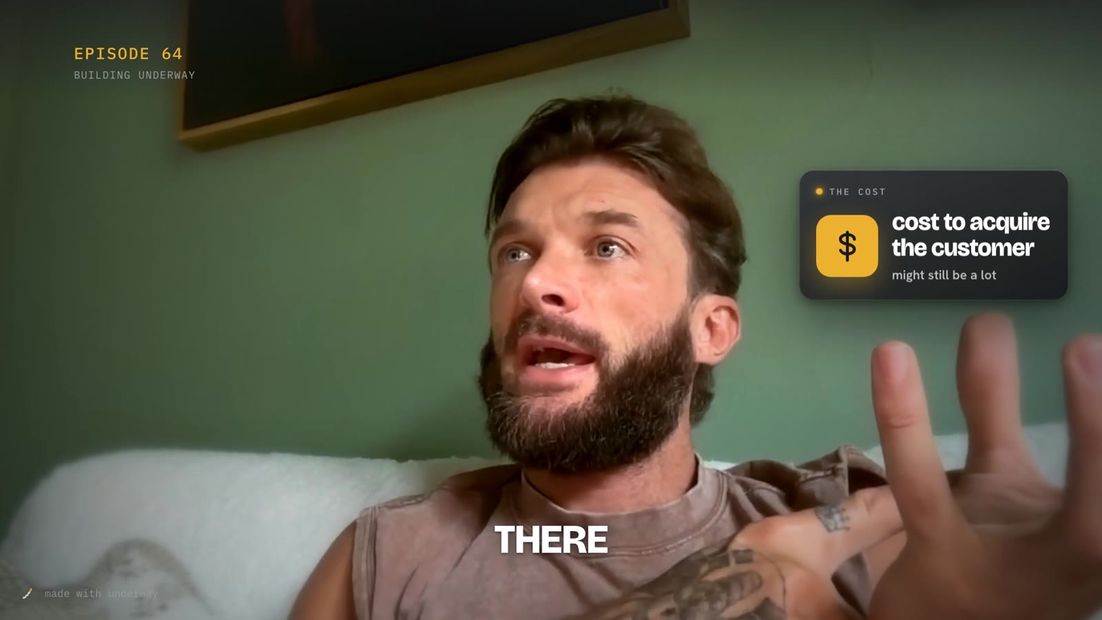 Rich talking to camera in episode 64 of Building Underway, with a dark glass card beside his head reading cost to acquire the customer, with a money icon